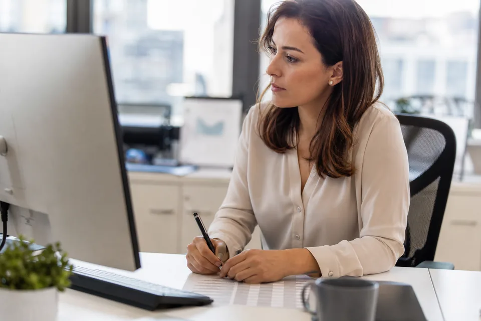 Sales operations admin reviewing a list of duplicate contacts on a monitor before merging them