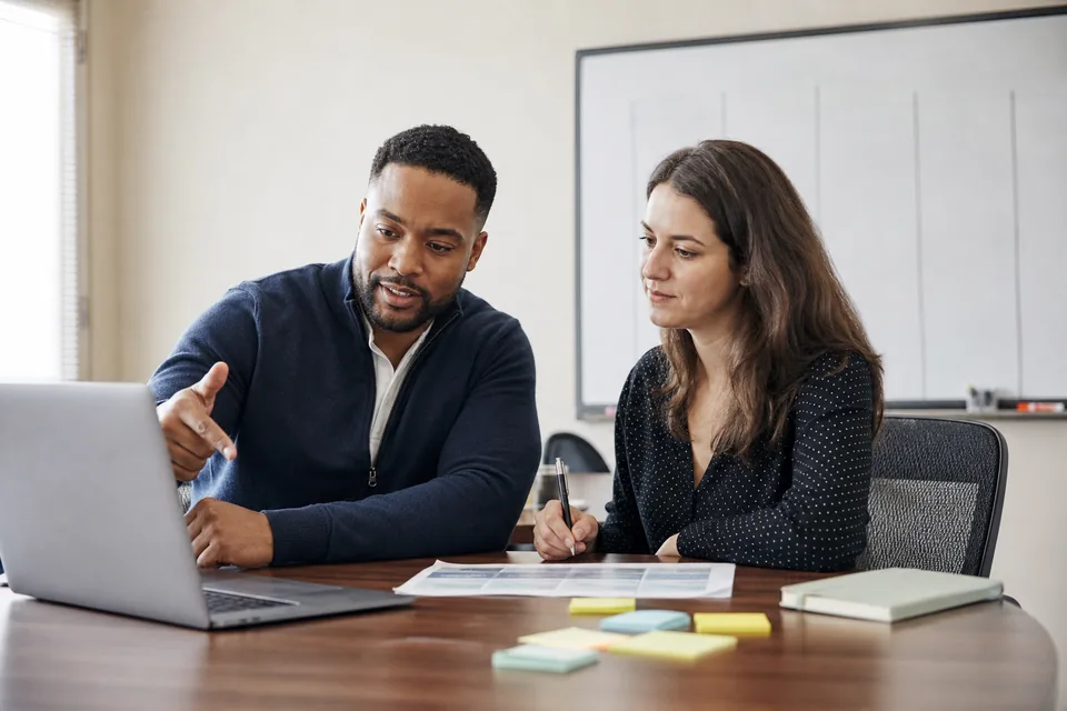 RevOps manager and analyst planning a CRM migration cutover with a laptop and a printed checklist